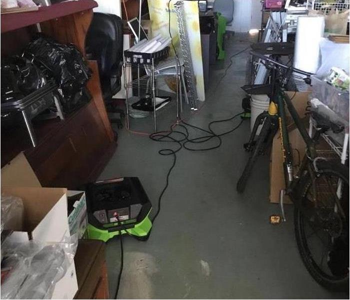 A room with a lot of stuff and bikes in it with drying machines on the ground