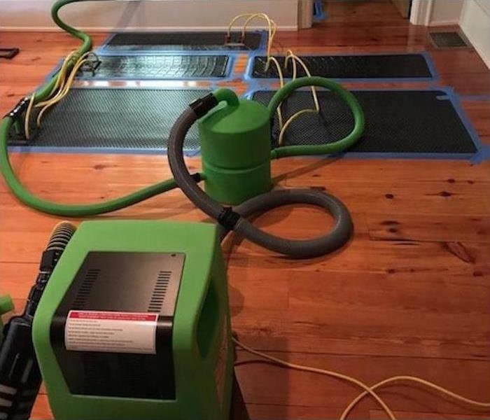 Water restoration machinery and mats on a hardwood floor