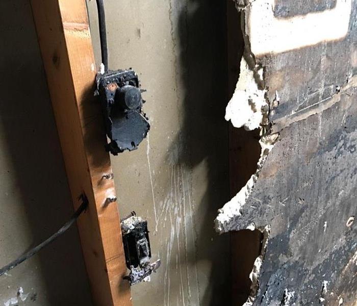 Electrical outlet on wall that is charred from fire