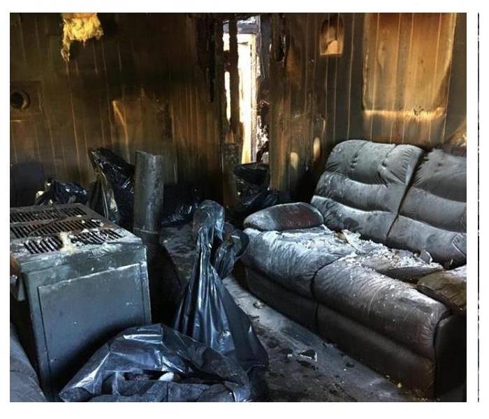 A room in a house with a burned floor, walls, ceiling, oven and couch all covered in fire ashes. 