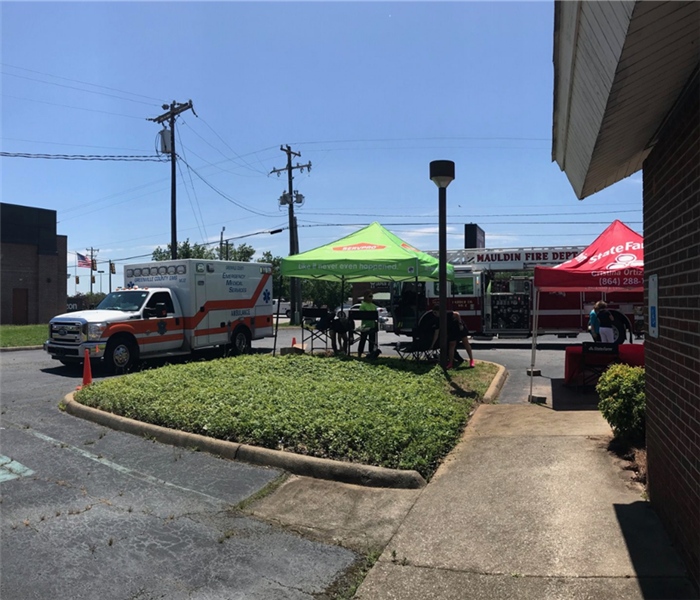 An ambulance, fire truck, and SERVPRO tent in a parking lot 