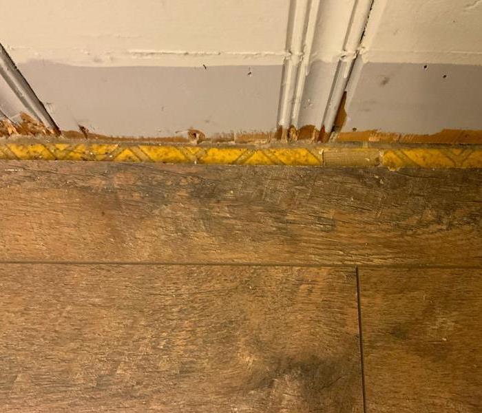 small piece of flooring removed to reveal tile underneath