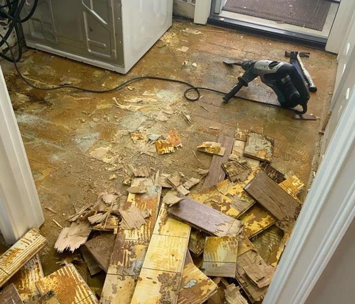 demolition process in a laundry room with flooring being ripped up