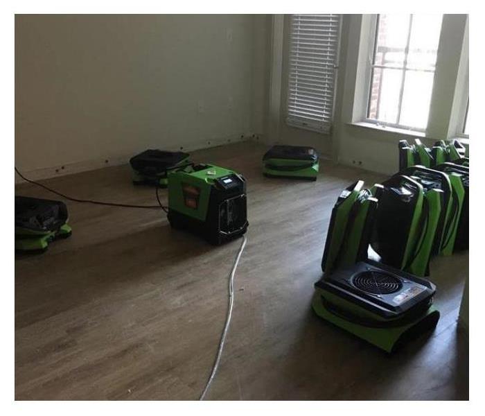Fans and water restoration machines sitting on hardwood floors