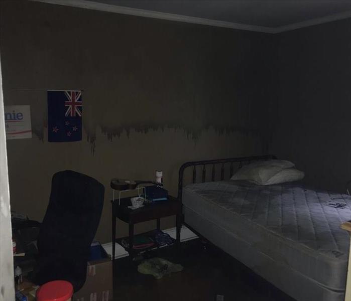 Bedroom that has soot damage on the walls from a fire that occurred in another part of the house.